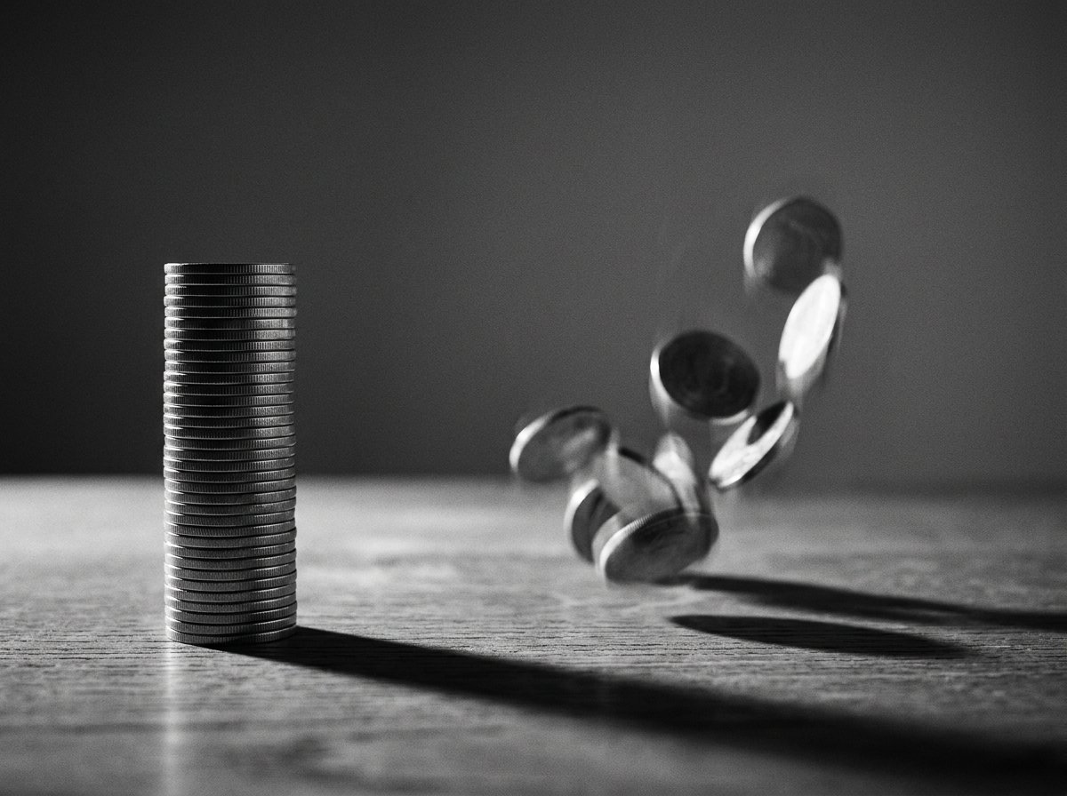 Monedas apiladas de forma estable junto a monedas rodando, como metáfora de un esquema garantizado frente a uno variable